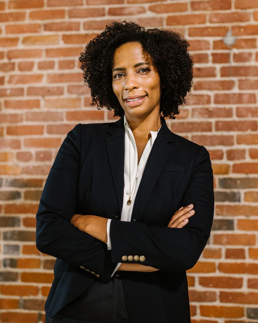 Entrepreneure souriante, en tailleur, bras croisés, posture confiante.