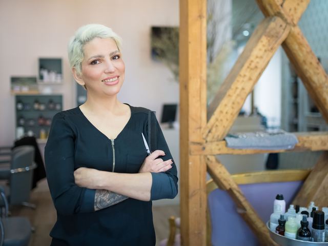 Responsable souriante dans un salon de coiffure moderne, prête à recevoir sa clientèle.